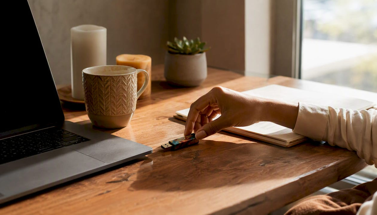 Hand placing USB drive on desk next to laptop